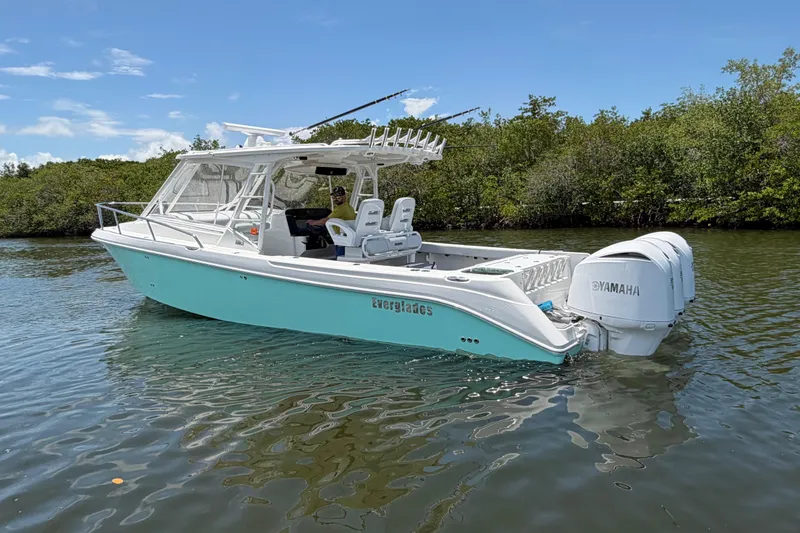 Slide: The Image of 2009 Everglades 350LX boat with Yamaha engines on calm water, surrounded by greenery. - 6