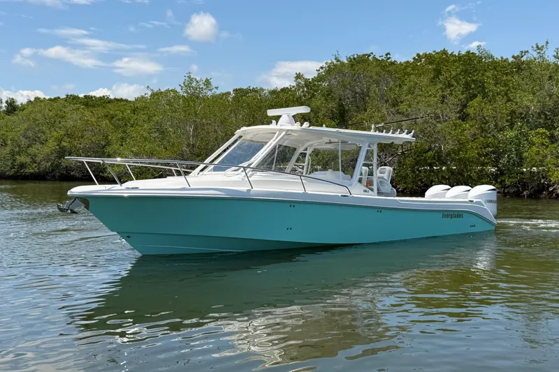Slide: The Image of 2009 Everglades 350LX boat cruising on calm water near lush greenery. - 8
