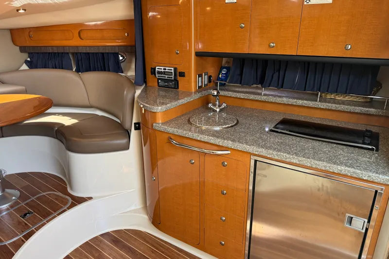 Slide: The Image of 2009 Chaparral Signature 330 interior with kitchenette, seating area, and wood accents. - 26