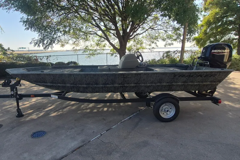 The Image of 2026 Tracker Grizzly 1648 SC boat on trailer, parked near a scenic lakeside view. - 0