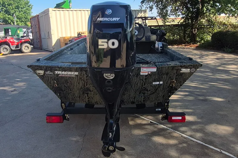 Slide: The Image of 2026 Tracker Grizzly 1648 SC boat with Mercury 50 engine, parked outdoors. - 6