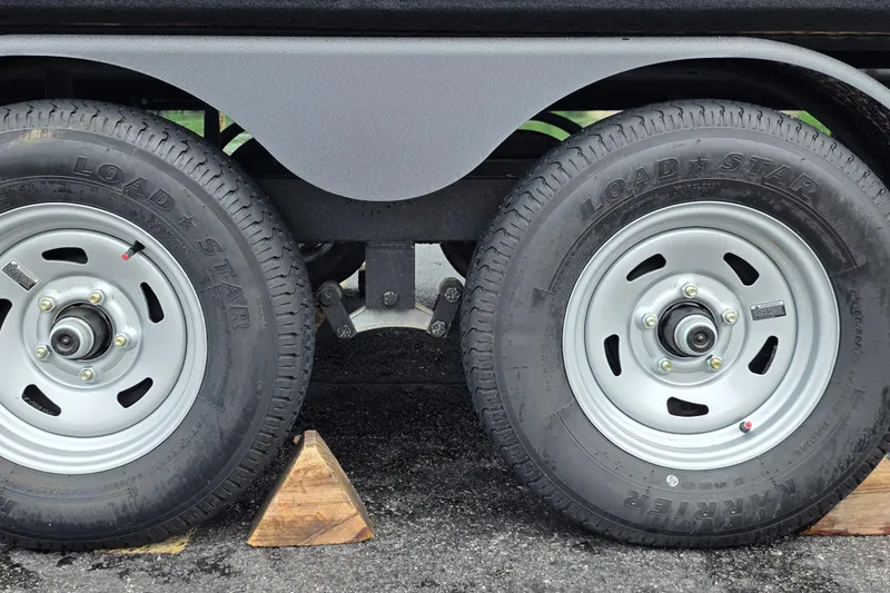 Slide: The Image of Trailer wheels of a 2026 Sun Tracker Party Barge 20 DLX, secured with wooden chocks. - 18