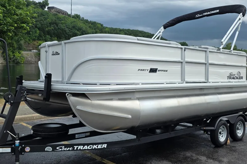 Slide: The Image of 2026 Sun Tracker Party Barge 20 DLX pontoon boat on trailer by a river. - 92