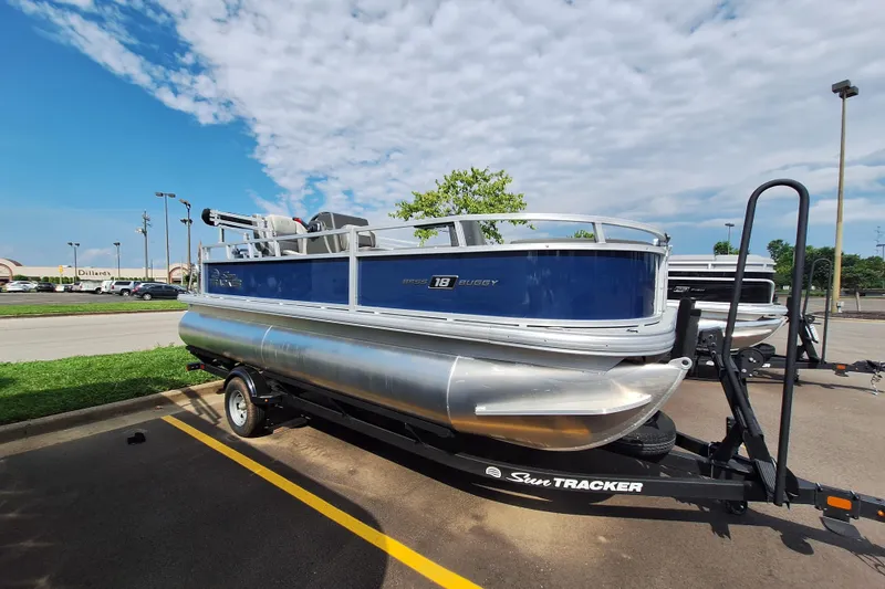 The Image of 2026 Sun Tracker Bass Buggy 18 DLX pontoon boat on trailer in parking lot. - 0