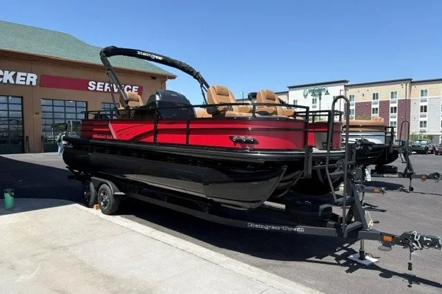 The Image of 2026 Ranger 223F boat in red and black on trailer, parked outside service center. - 0