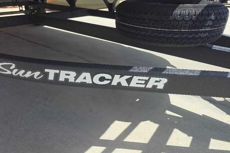 Slide: The Image of 2026 Sun Tracker Bass Buggy 18 DLX trailer with spare tire, parked on concrete. - 6