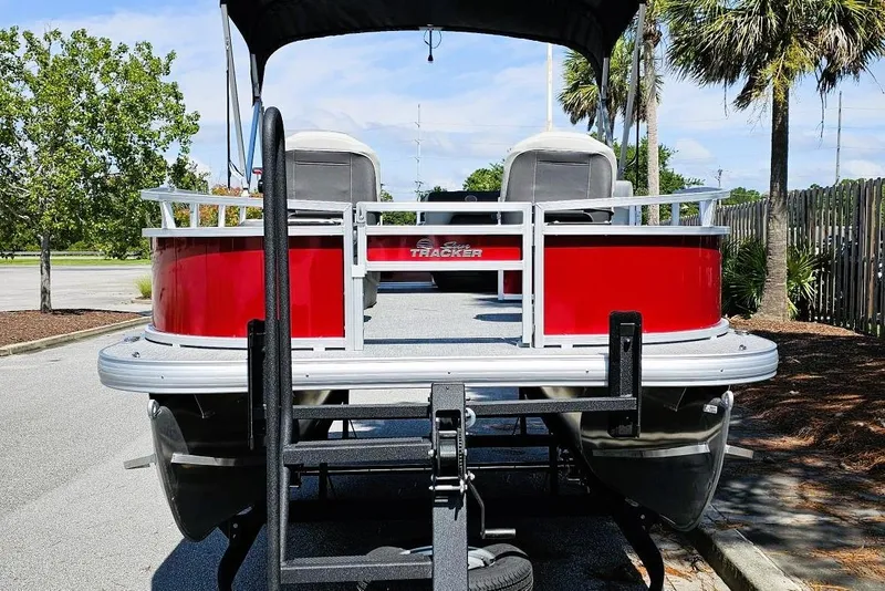 Slide: The Image of 2026 Sun Tracker Bass Buggy 16 XL Select pontoon boat, red exterior, parked outdoors. - 4