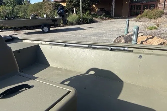 Slide: The Image of 2026 Tracker Grizzly 1648 SC boat interior, showcasing seating and storage in a driveway setting. - 7