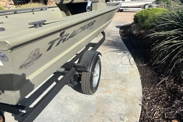 Slide: The Image of 2026 Tracker Grizzly 1648 SC boat on trailer, parked on a concrete path. - 8