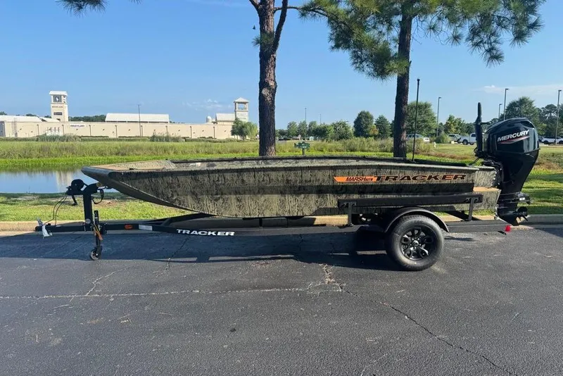The Image of 2026 Tracker Grizzly 1756 T Marsh boat on trailer, parked near a pond. - 0