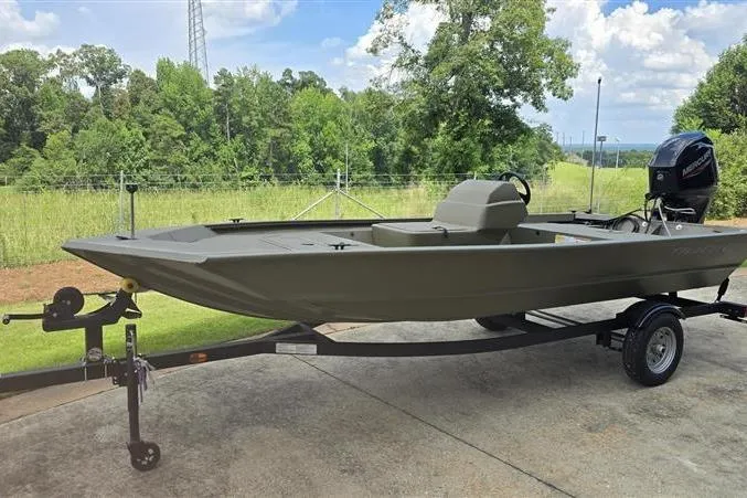 Slide: The Image of 2026 Tracker Grizzly 1648 SC boat on trailer, parked outdoors with lush greenery background. - 6