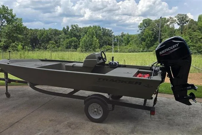 Slide: The Image of 2026 Tracker Grizzly 1648 SC boat with Mercury engine on trailer, outdoors. - 2