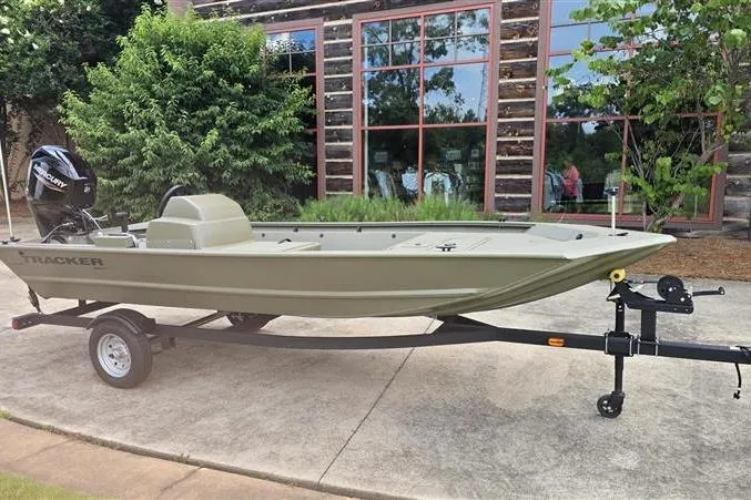 Slide: The Image of 2026 Tracker Grizzly 1648 SC boat on trailer, parked outdoors near rustic building. - 3