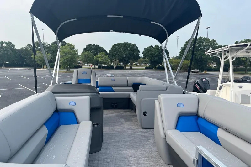 Slide: The Image of 2026 Sun Tracker Party Barge 20 DLX with spacious seating and canopy in a parking lot. - 7