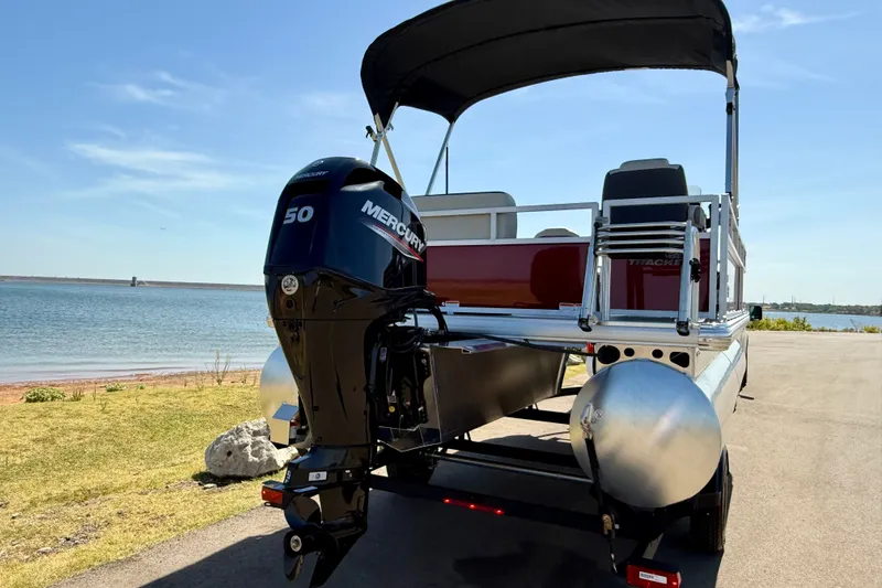 Slide: The Image of 2026 Sun Tracker Bass Buggy 16 XL Select pontoon boat with Mercury engine by the water. - 17