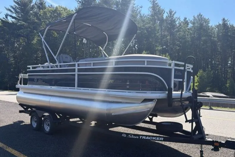 Slide: The Image of 2026 Sun Tracker SportFish 20 DLX pontoon boat on trailer, parked outdoors. - 2