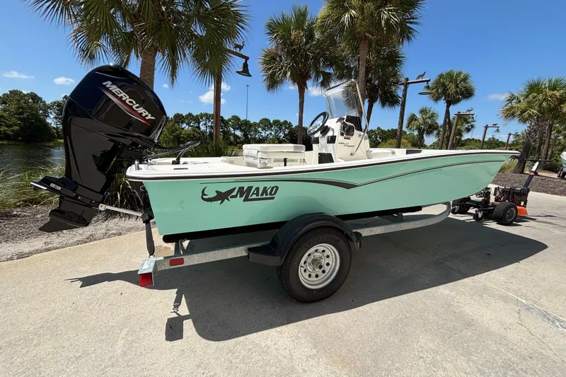 Slide: The Image of 2026 Mako Pro Skiff 15 CC boat on trailer, parked near palm trees. - 2