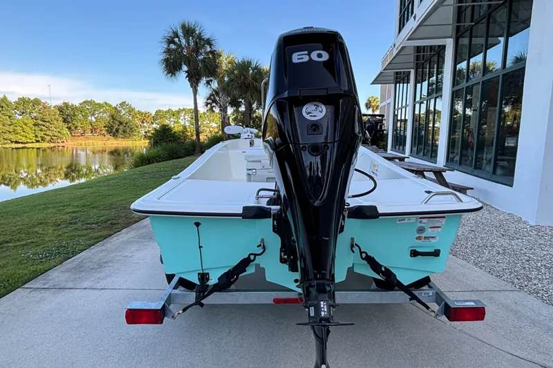 Slide: The Image of 2026 Mako Pro Skiff 15 CC boat with 60 HP engine, parked near a scenic lake. - 5