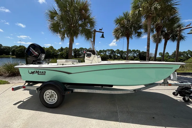 Slide: The Image of 2026 Mako Pro Skiff 15 CC boat on trailer, parked near palm trees. - 1