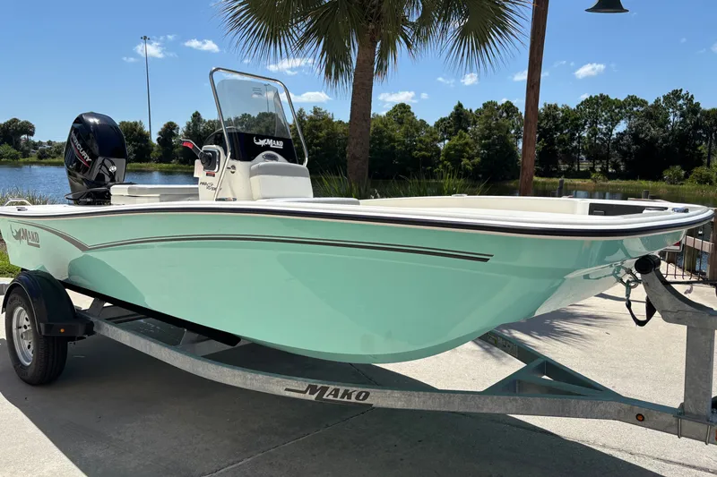 The Image of 2026 Mako Pro Skiff 15 CC boat on trailer by a lake under a clear sky. - 0