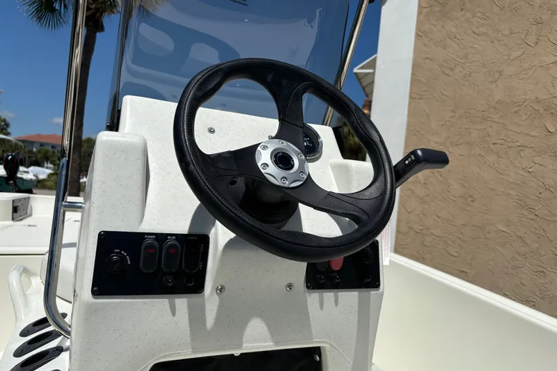 Slide: The Image of 2026 Mako Pro Skiff 15 CC steering console with controls and black steering wheel. - 11