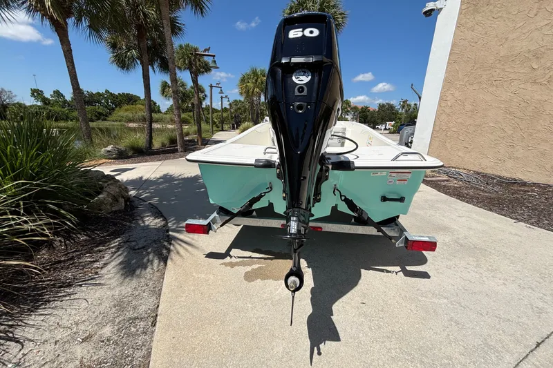 Slide: The Image of 2026 Mako Pro Skiff 15 CC boat on trailer, parked outdoors under palm trees. - 3