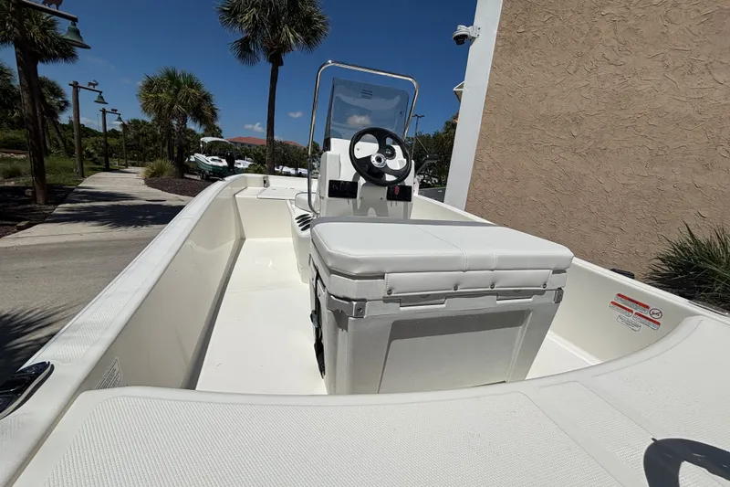 Slide: The Image of 2026 Mako Pro Skiff 15 CC boat with center console and seating, parked outdoors. - 8