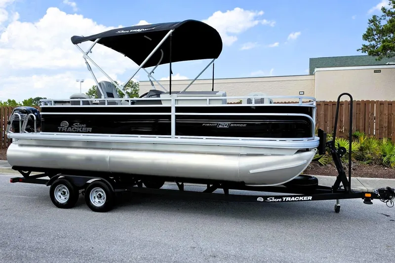 Slide: The Image of 2026 Sun Tracker Fishin' Barge 20 DLX pontoon boat on trailer, parked outdoors. - 5