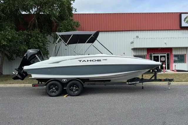 The Image of 2026 Tahoe 2150 boat on trailer, parked outside a building with red and white facade. - 0