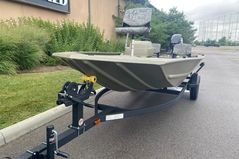 Slide: The Image of 2026 Tracker Grizzly 1754 SC boat on trailer, parked outdoors near greenery. - 2