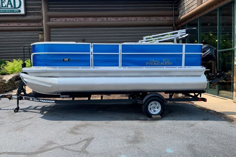 The Image of 2026 Sun Tracker Party Barge 18 DLX pontoon boat on trailer, parked outdoors. - 0