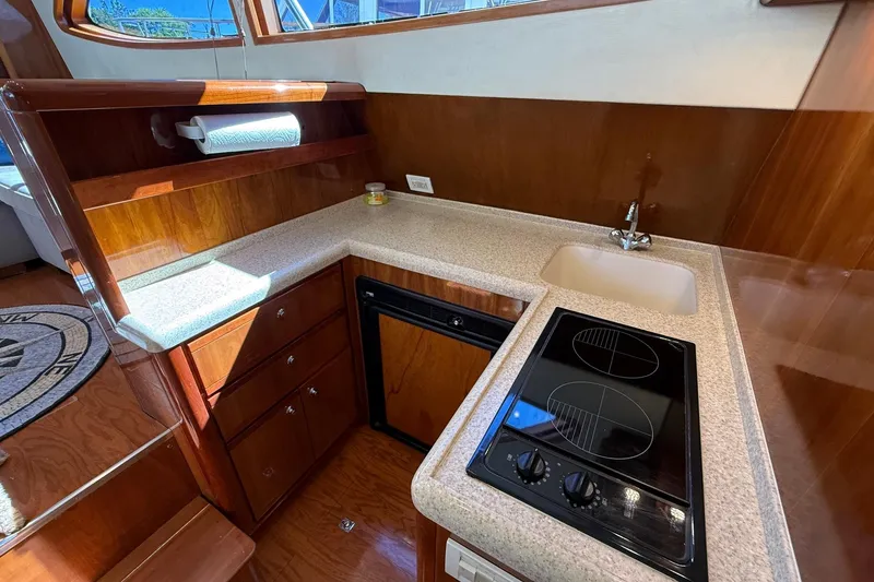 Slide: The Image of 2002 Bertram 390 Convertible yacht kitchen with stove, sink, and wooden cabinetry. - 17
