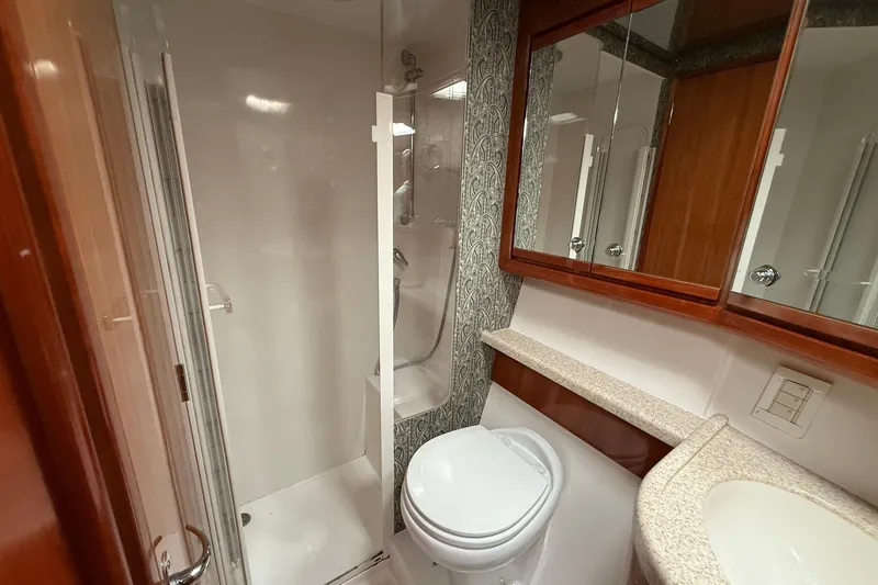 Slide: The Image of Bathroom interior of 2002 Bertram 390 Convertible yacht, featuring shower, toilet, and mirrored cabinets. - 24