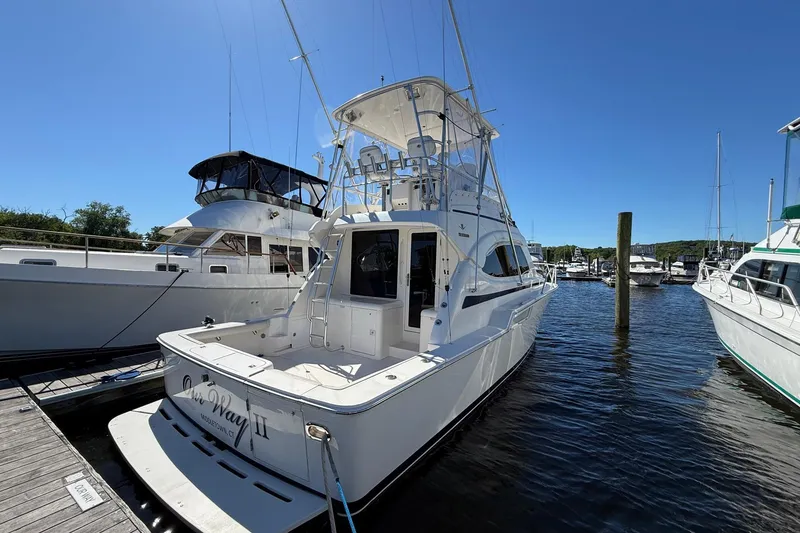 Slide: The Image of 2002 Bertram 390 Convertible yacht docked at marina under clear blue sky. - 4