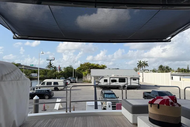 Slide: The Image of View from 2024 Sirena 88 yacht, overlooking a marina with parked vehicles and palm trees. - 89