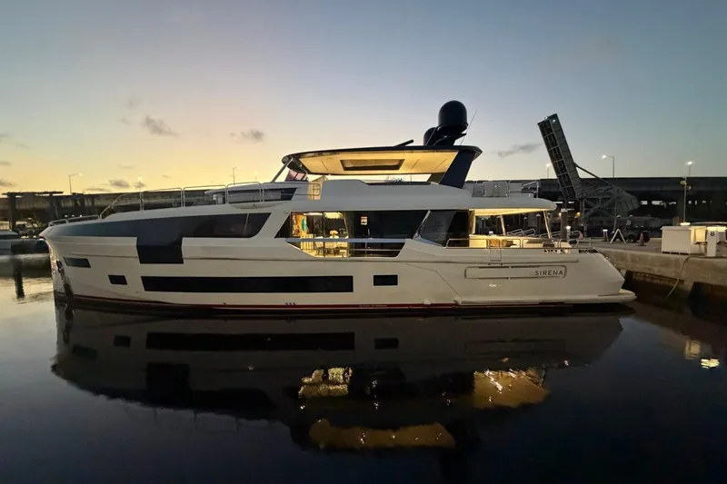 Slide: The Image of 2024 Sirena 88 yacht docked at sunset, reflecting on calm water. - 63