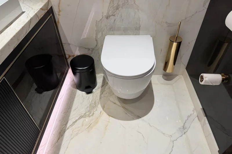 Slide: The Image of Luxurious bathroom with marble flooring, modern toilet, and gold accents on a 2024 Sirena 88 yacht. - 77