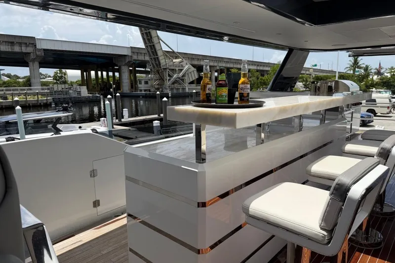 Slide: The Image of Luxurious 2024 Sirena 88 yacht bar area with stools and drinks, docked near a bridge. - 13