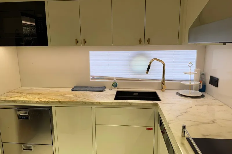 Slide: The Image of Modern yacht kitchen with marble countertops, gold faucet, and sleek cabinetry in a 2024 Sirena 88. - 152