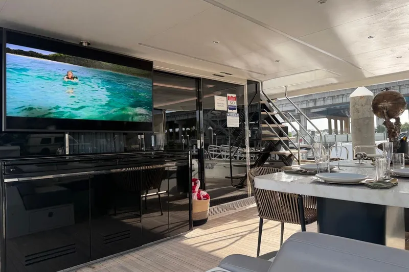 Slide: The Image of Luxurious 2024 Sirena 88 yacht interior with dining area and TV displaying ocean scene. - 23