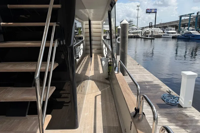 Slide: The Image of 2024 Sirena 88 yacht docked, showcasing sleek design and luxurious wooden deck. - 97