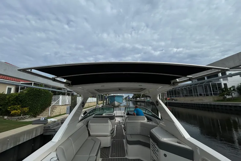 Slide: The Image of 2024 Sea Ray SLX 310 Outboard boat cruising through a canal under a cloudy sky. - 140