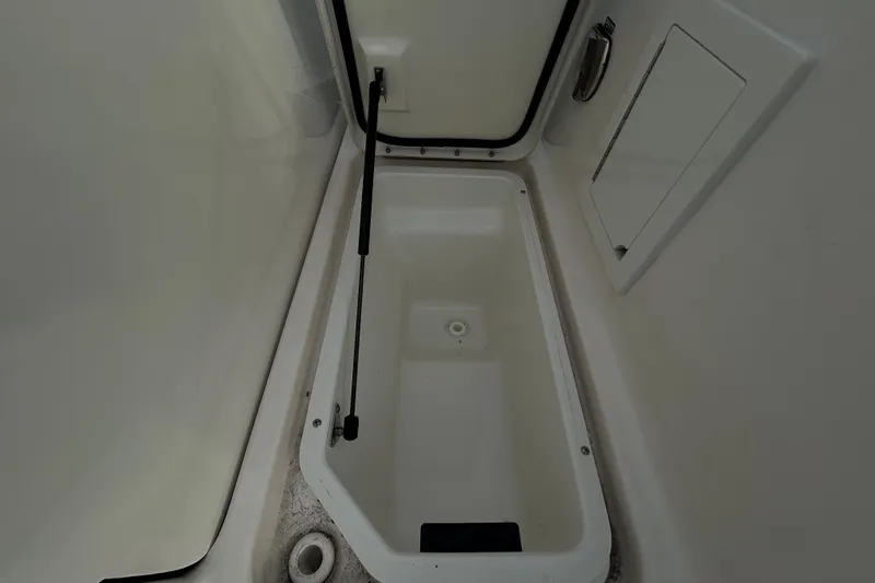 Slide: The Image of 2024 Sea Ray SLX 310 Outboard storage compartment, open lid, white interior. - 18