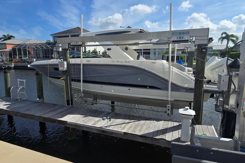 Slide: The Image of 2024 Sea Ray SLX 310 Outboard boat docked on a lift in a sunny marina. - 2