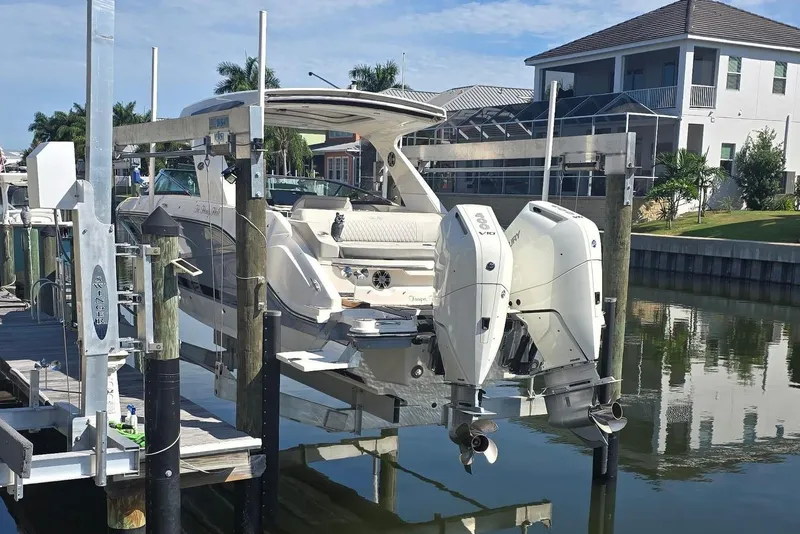 Slide: The Image of A Sea Ray SLX 310 Outboard boat on a lift in a calm canal. - 3