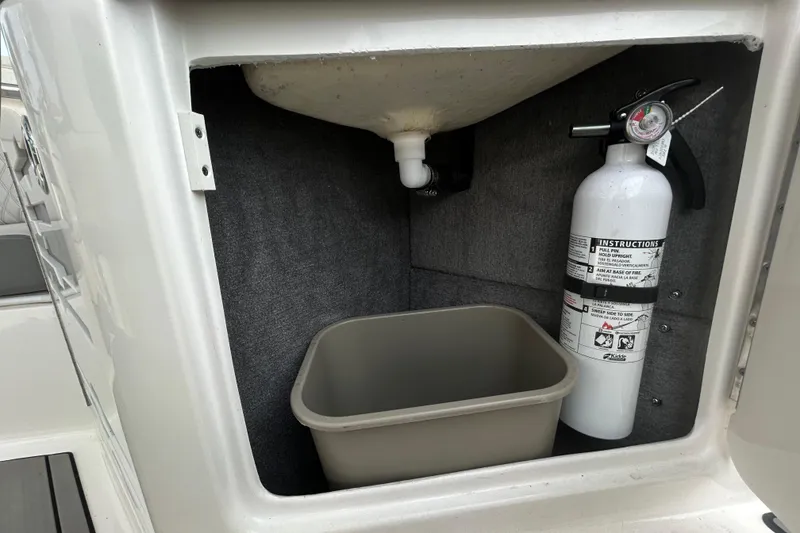 Slide: The Image of 2024 Sea Ray SLX 310 Outboard storage compartment with fire extinguisher and bin. - 46