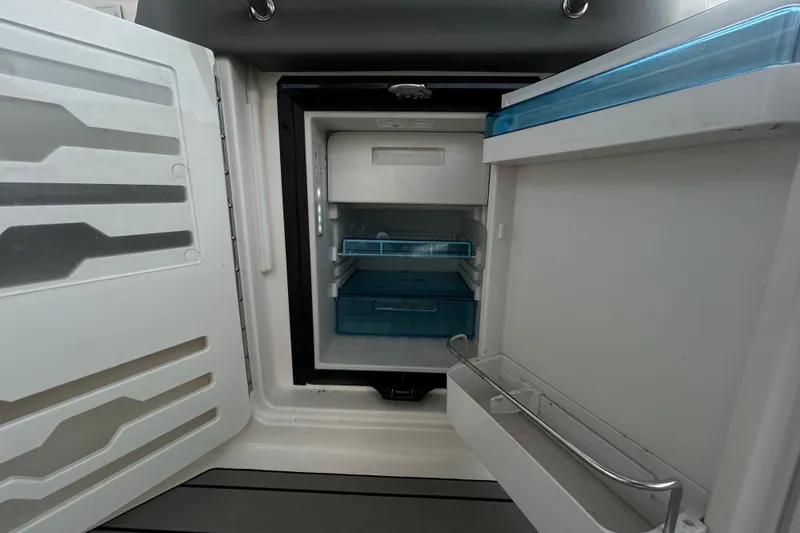 Slide: The Image of Open refrigerator inside 2024 Sea Ray SLX 310 Outboard boat, showcasing storage compartments. - 47