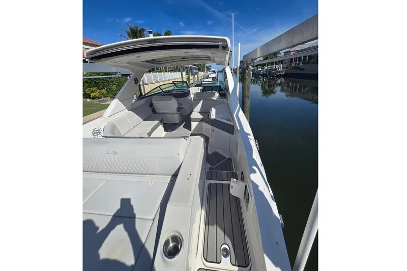 Slide: The Image of A modern boat with white seating and open deck, docked by calm water. - 5