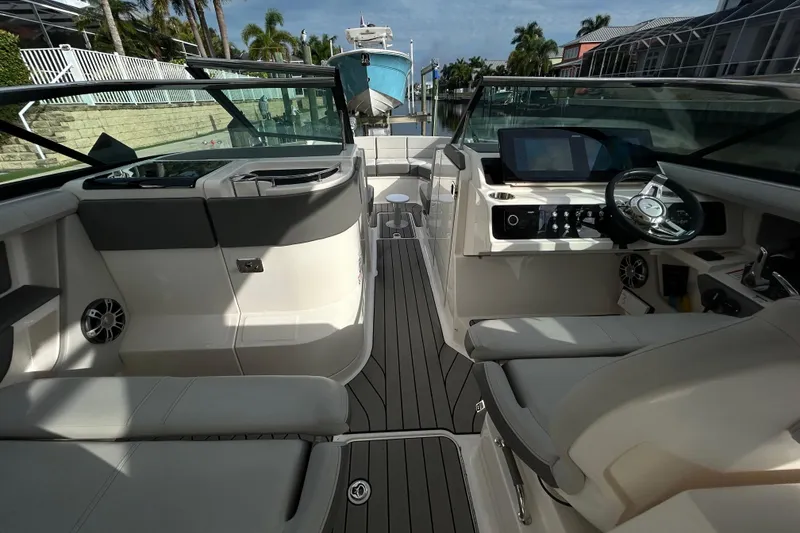 Slide: The Image of 2024 Sea Ray SLX 310 Outboard interior with modern helm and seating, docked near palm trees. - 62