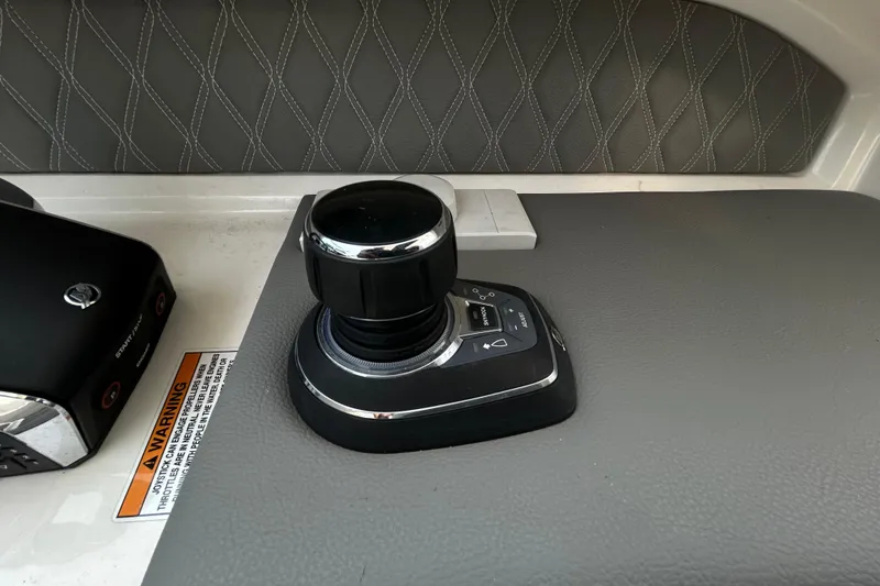 Slide: The Image of 2024 Sea Ray SLX 310 Outboard joystick control on a textured dashboard. - 69